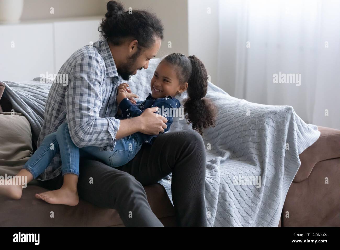 Playful happy African dad tickling cheerful little daughter kid Stock