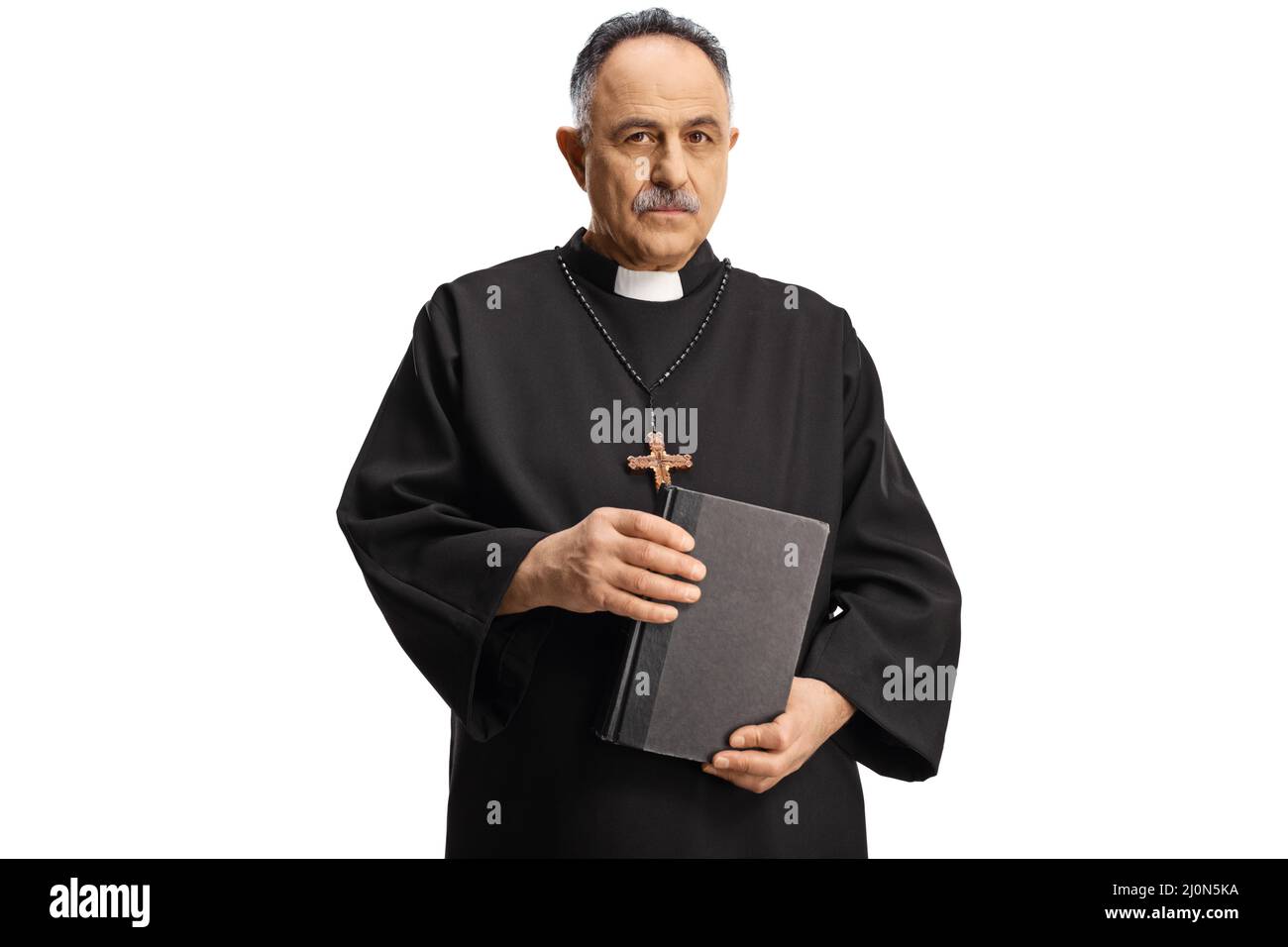 Serious priest holding a bible and looking at camera isolated on white ...