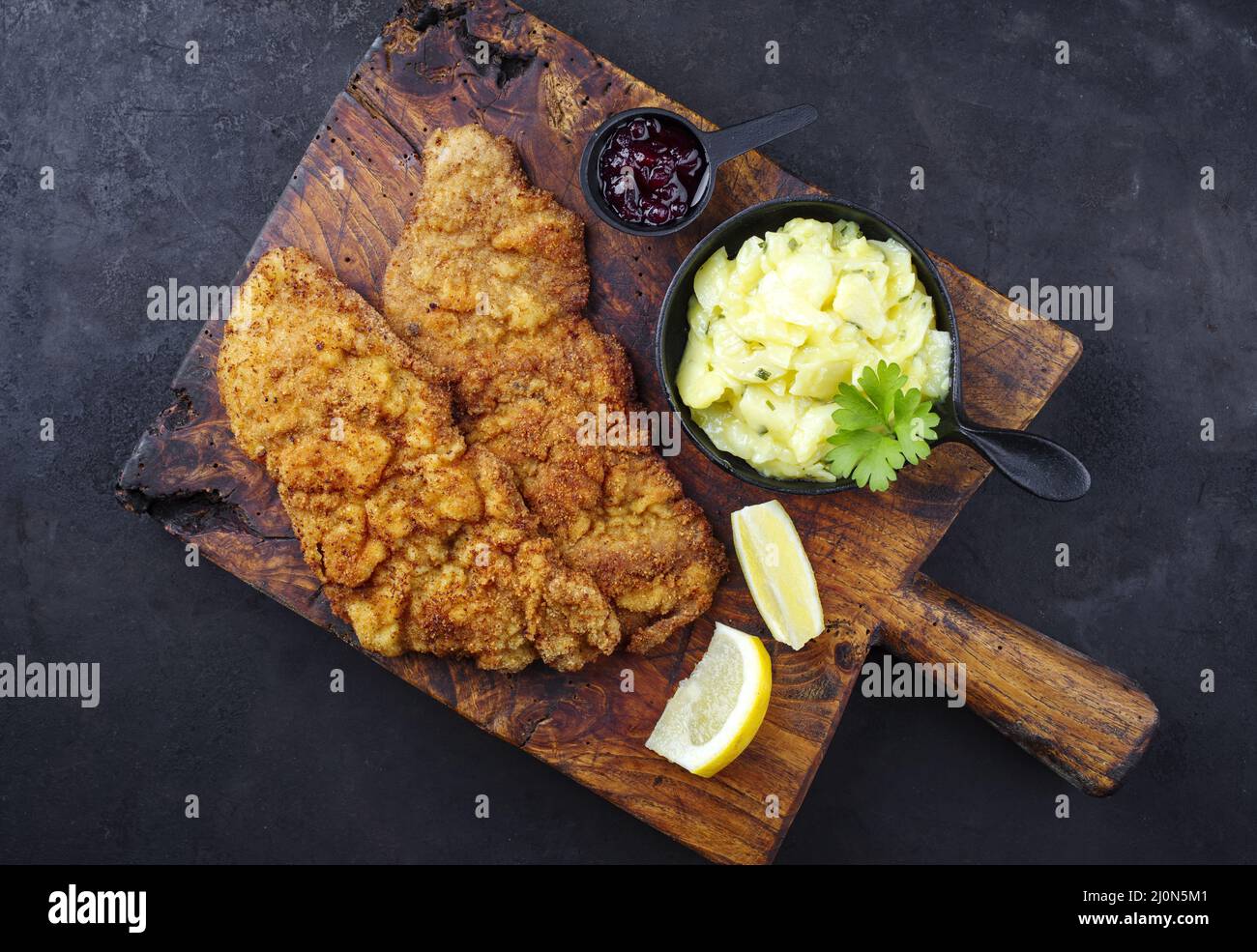 Traditional deepfried schnitzel with potato salad and cranberries