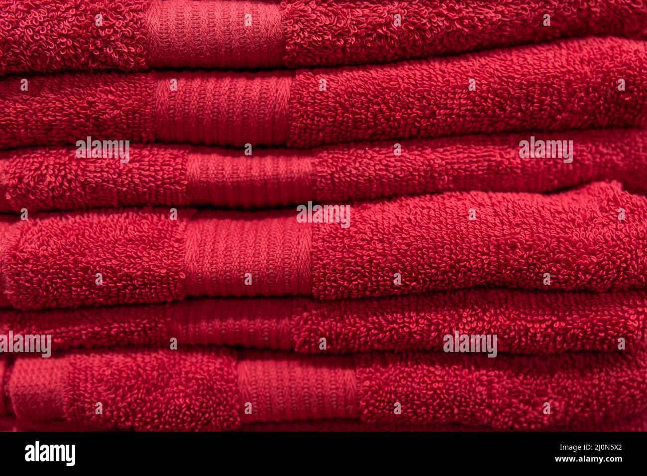 Textured red bath towels stacked close up. Stock Photo