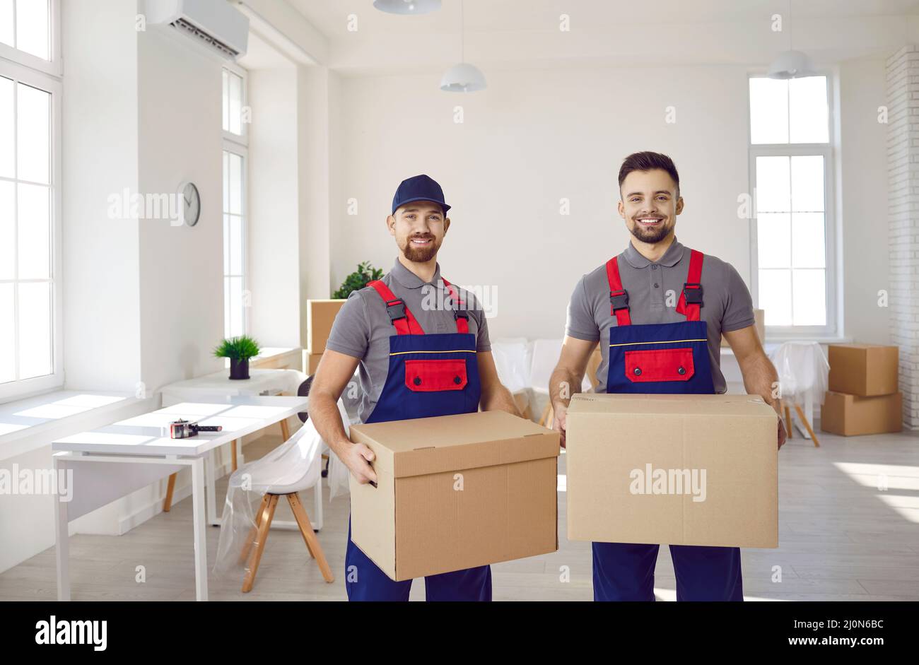 Male loaders with cardboard boxes in their hands help client to move to ...