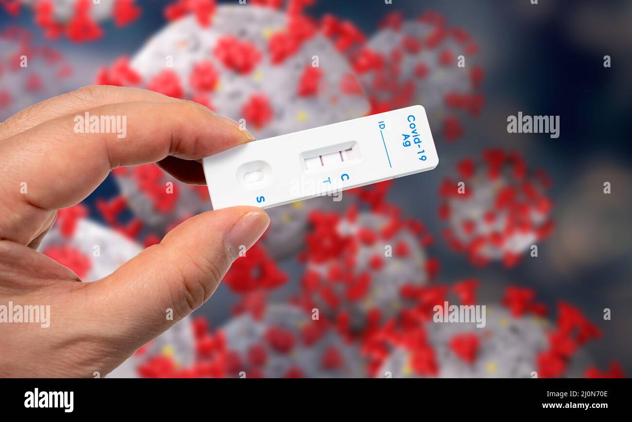A male hand holding a COVID19 rapid antigen test kit with two red