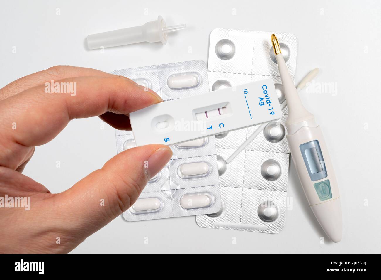 A male hand holding a COVID19 rapid antigen test kit with two red