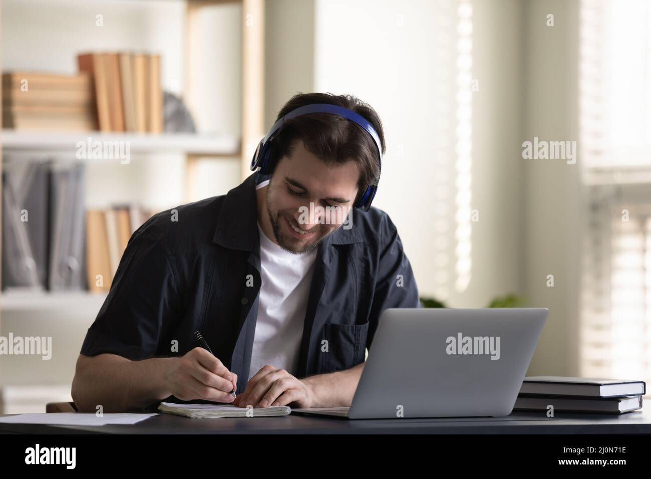 Cheerful student guy in headphones enjoying online studying at laptop Stock Photo