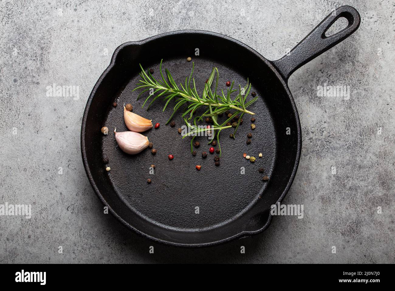 https://c8.alamy.com/comp/2J0N7J0/black-cast-iron-frying-pan-with-rosemary-garlic-pepper-top-view-2J0N7J0.jpg