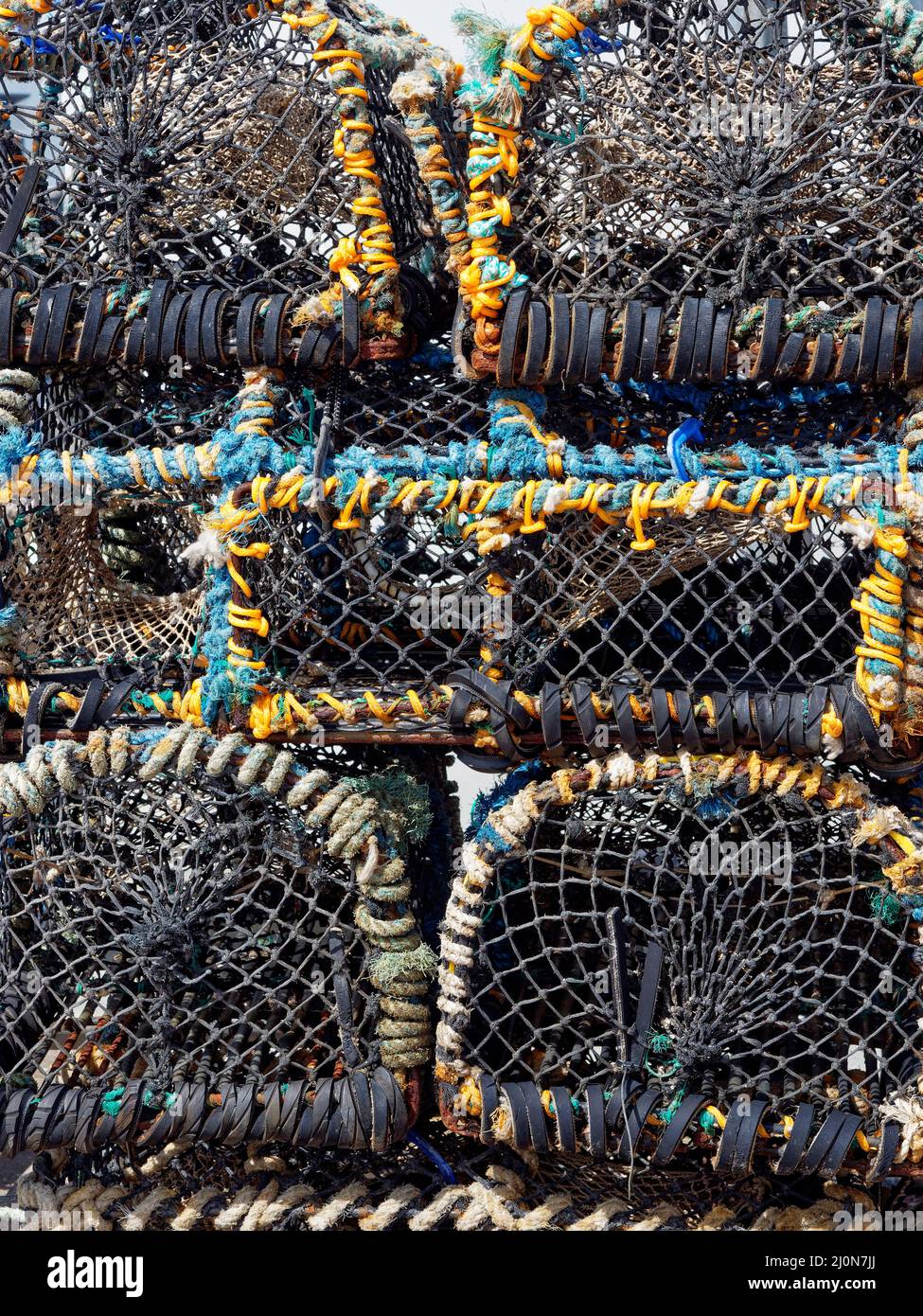 Stacked Crab and Lobster Pots in Close up on one of the Quays at Seahouses Harbour on the North East Coast of England. Stock Photo