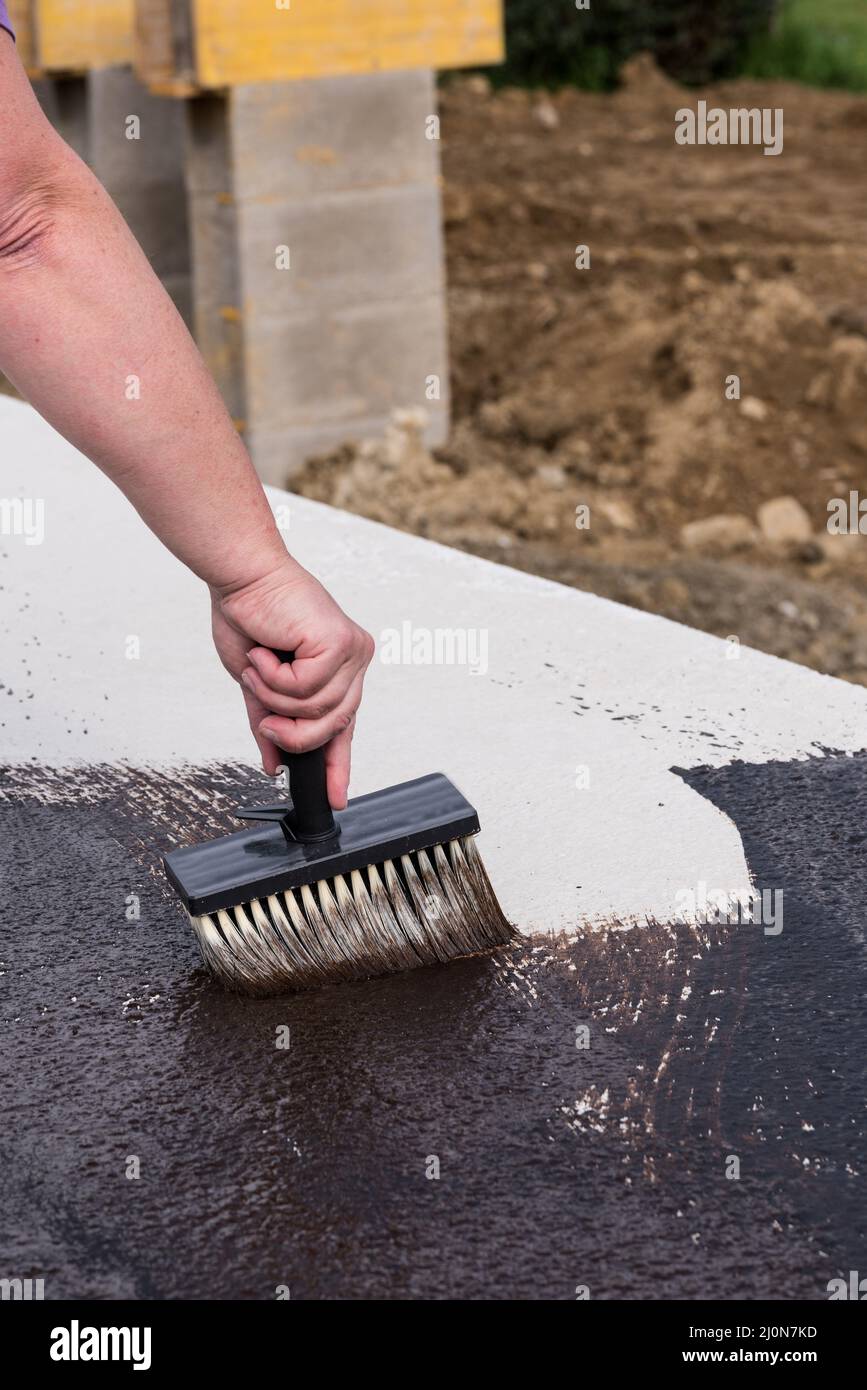 Craftsman paints the basement ceiling with bitumen when building a house - close-up Stock Photo