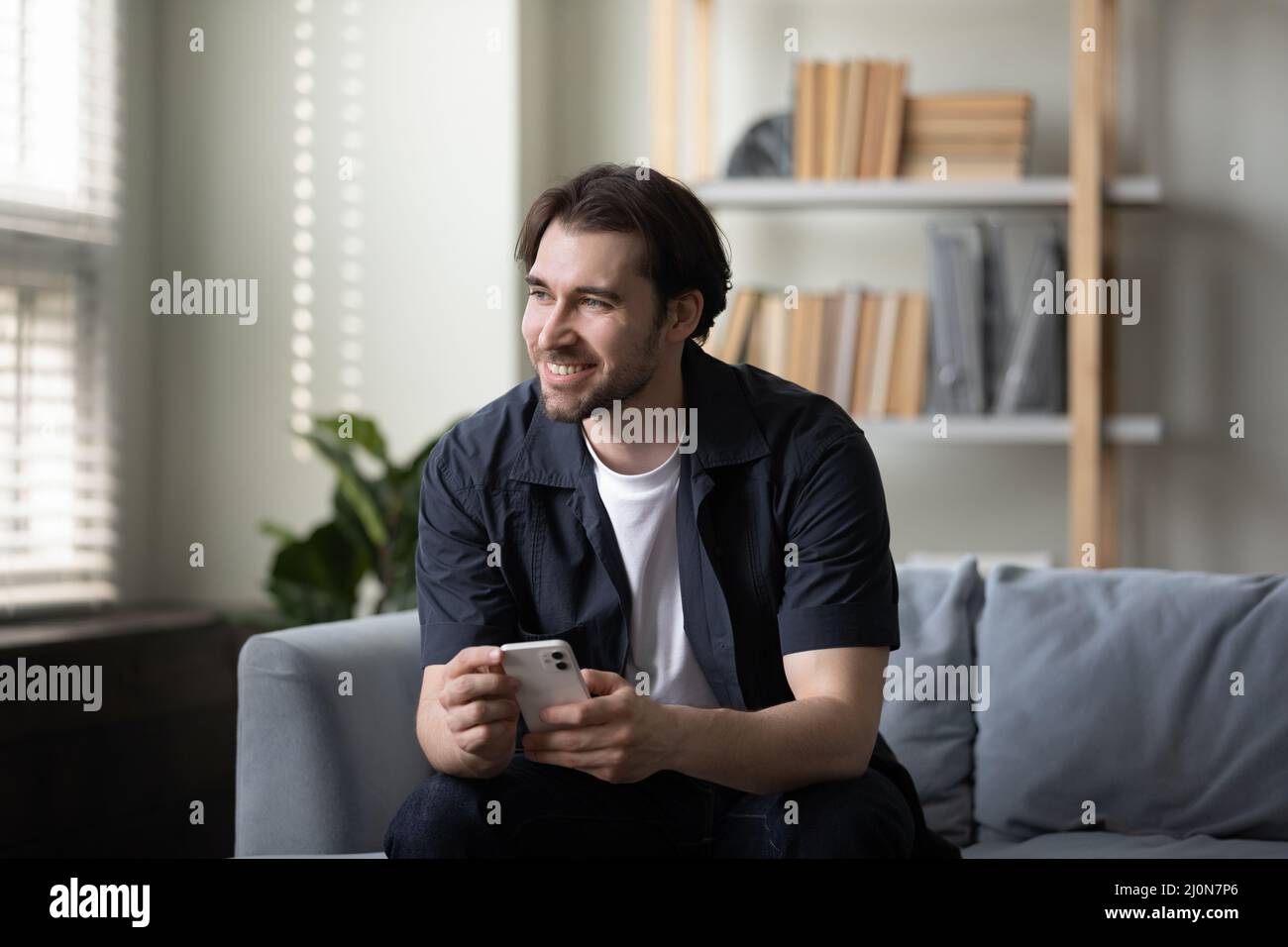 Happy cheerful cellphone user guy holding mobile phone Stock Photo