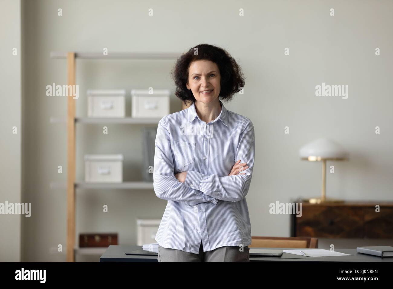 Confident mature business leader woman standing with hands folded Stock Photo