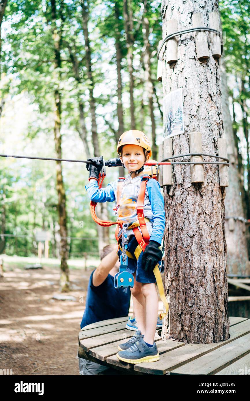 Boy in a helmet with safety equipment stands on a wooden platform Stock Photo