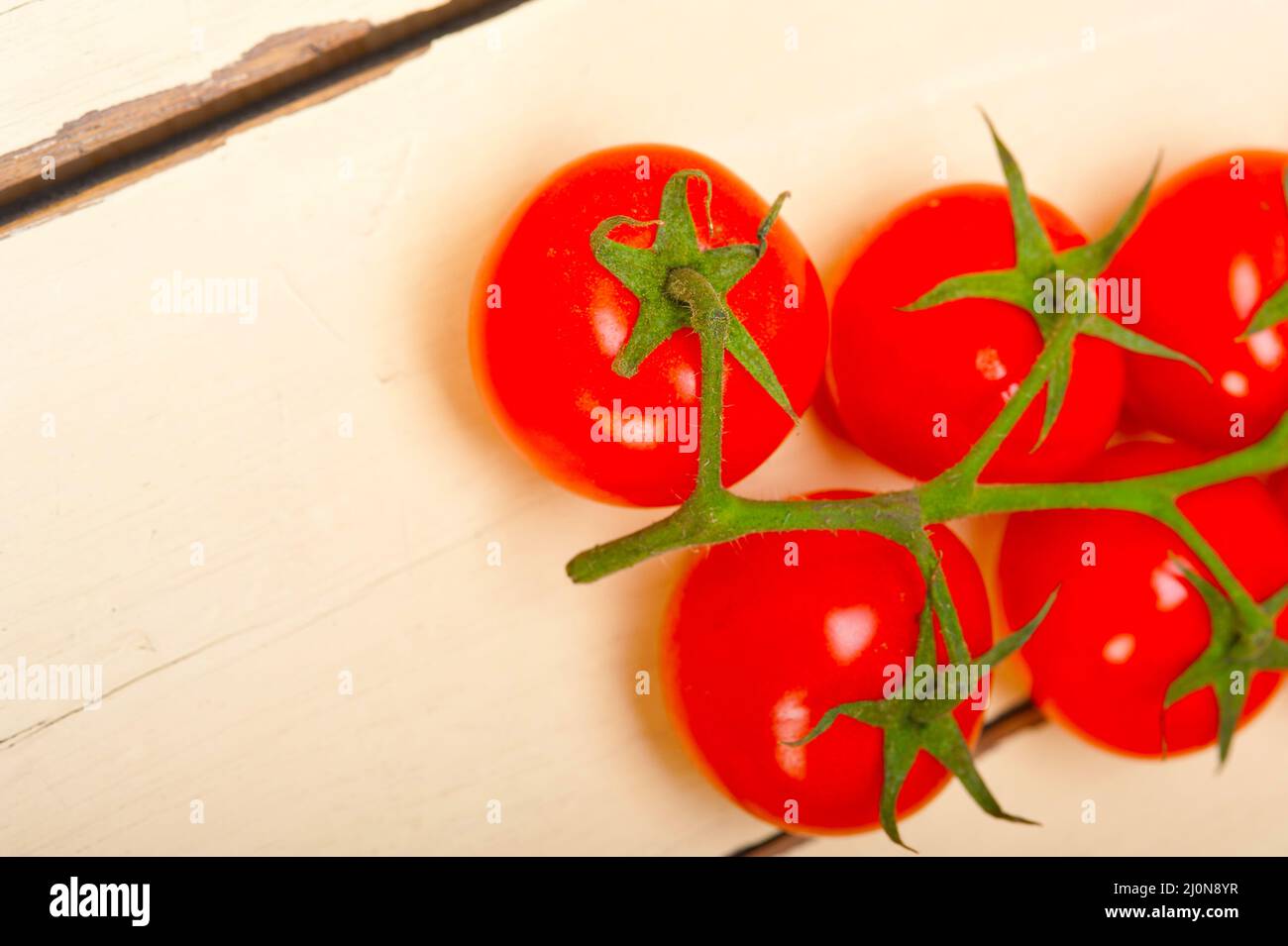 fresh cherry tomatoes on a cluster over rustic wood table Stock Photo ...
