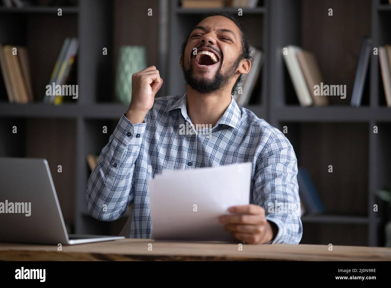 Excited euphoric Black student guy receiving admission letter from school Stock Photo