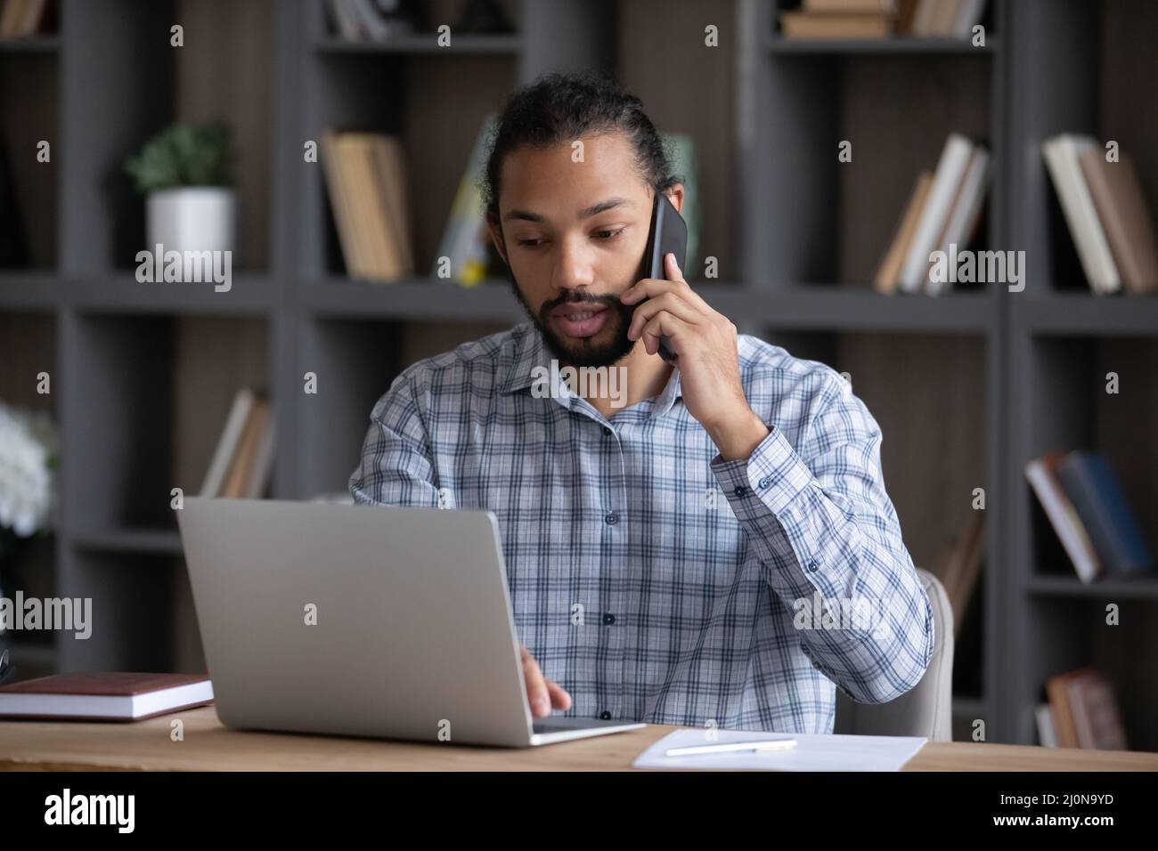 Serious busy African business professional guy working at laptop Stock Photo