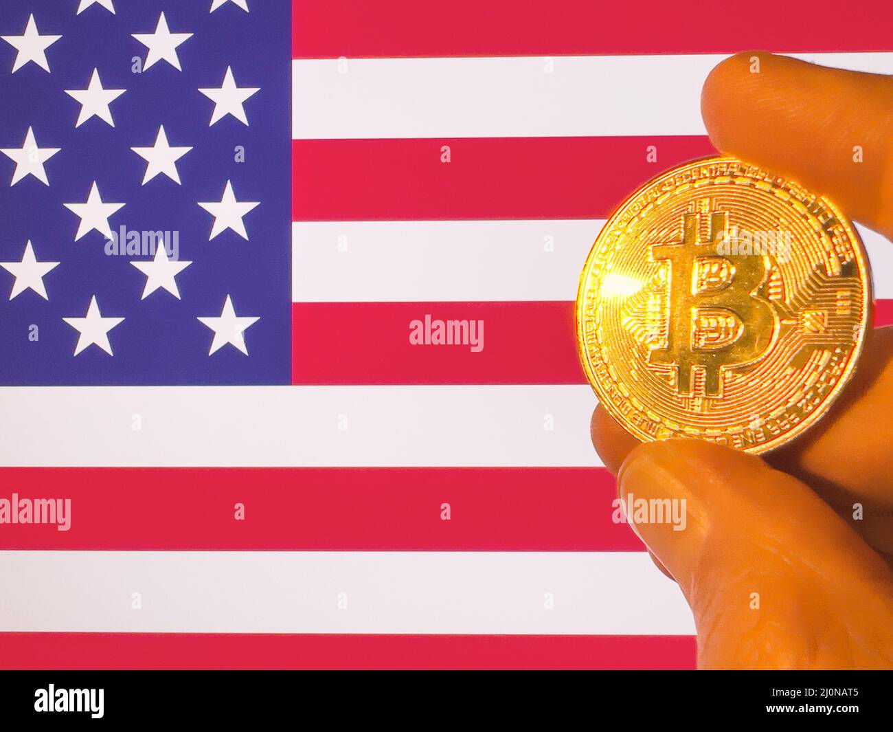 Holding a physical golden Bitcoin over the American flag. USA as cryptocurrency and blockchain technology investor. Financial background Stock Photo