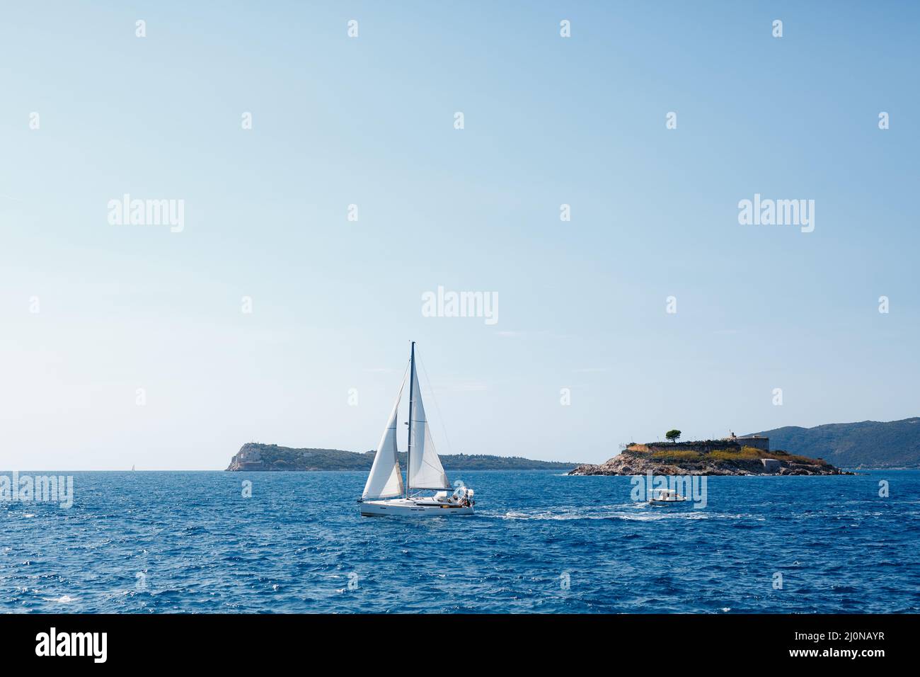 Sailboat sails past the coast of Mamula Island Stock Photo