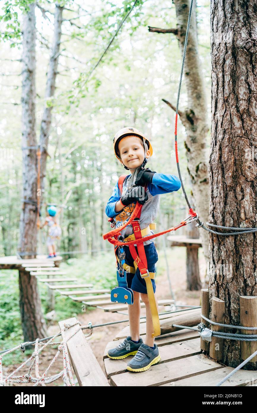 Boy stands on a wooden platform in a safety gear at an amusement park Stock Photo