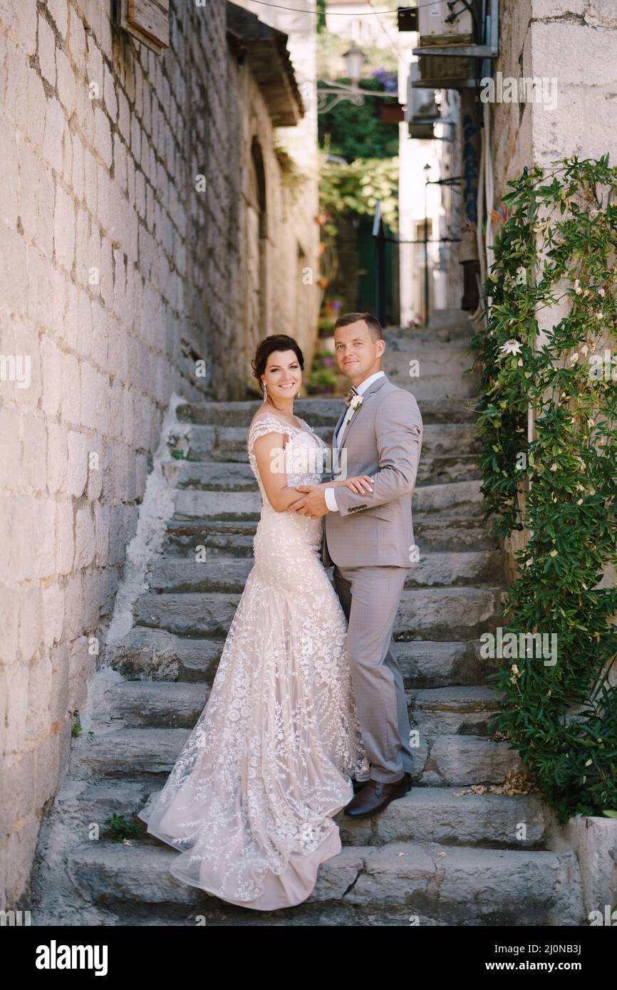 Bride and groom stand on the stone steps near the ancient building ...