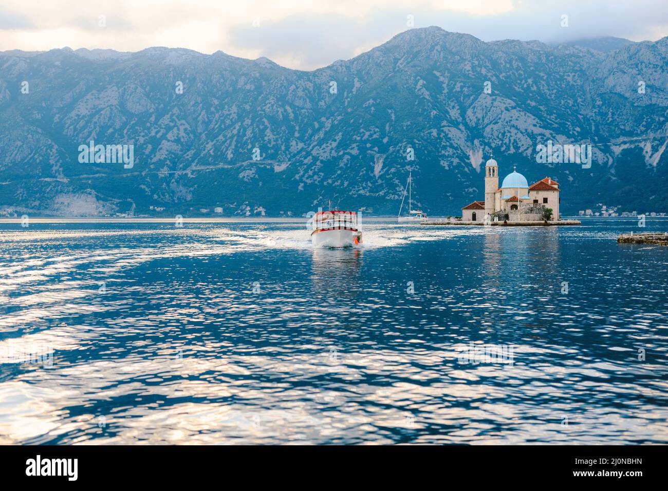 Boat sails from the island of Gospa od Skrpjela. Montenegro Stock Photo