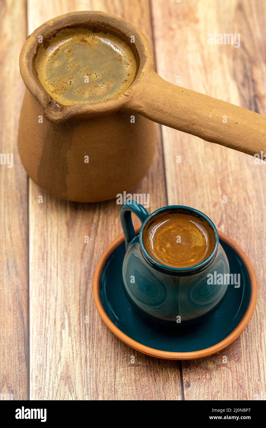 Turkish coffee on wood floor. Rustic cup and earthen coffee pot Stock Photo