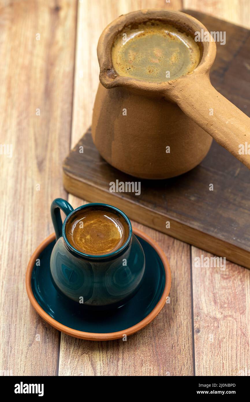 Turkish coffee on wood floor. Rustic cup and earthen coffee pot Stock Photo