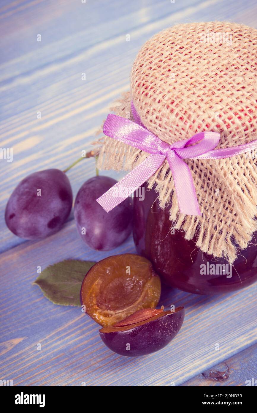 Fresh homemade plum marmalade in jar with ripe fruits on wooden boards, concept of healthy sweet dessert Stock Photo