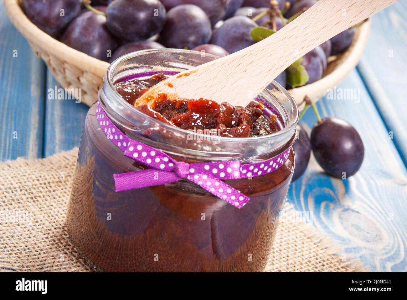 Wooden knife and plum marmalade or jam in glass jar, concept of healthy sweet snack or dessert Stock Photo