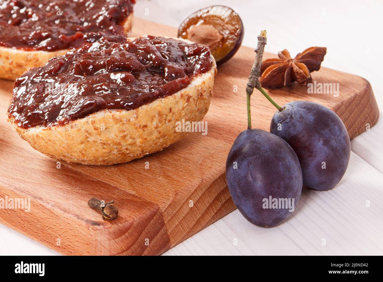 Sandwiches with plum marmalade or jam on wooden cutting board, concept of delicious breakfast Stock Photo