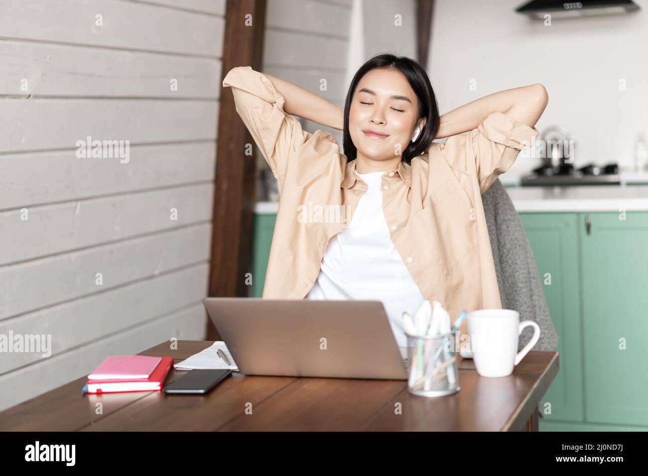Work from home and distance education concept. Young asian girl finished online course, stretching and lay back on chair, restin Stock Photo