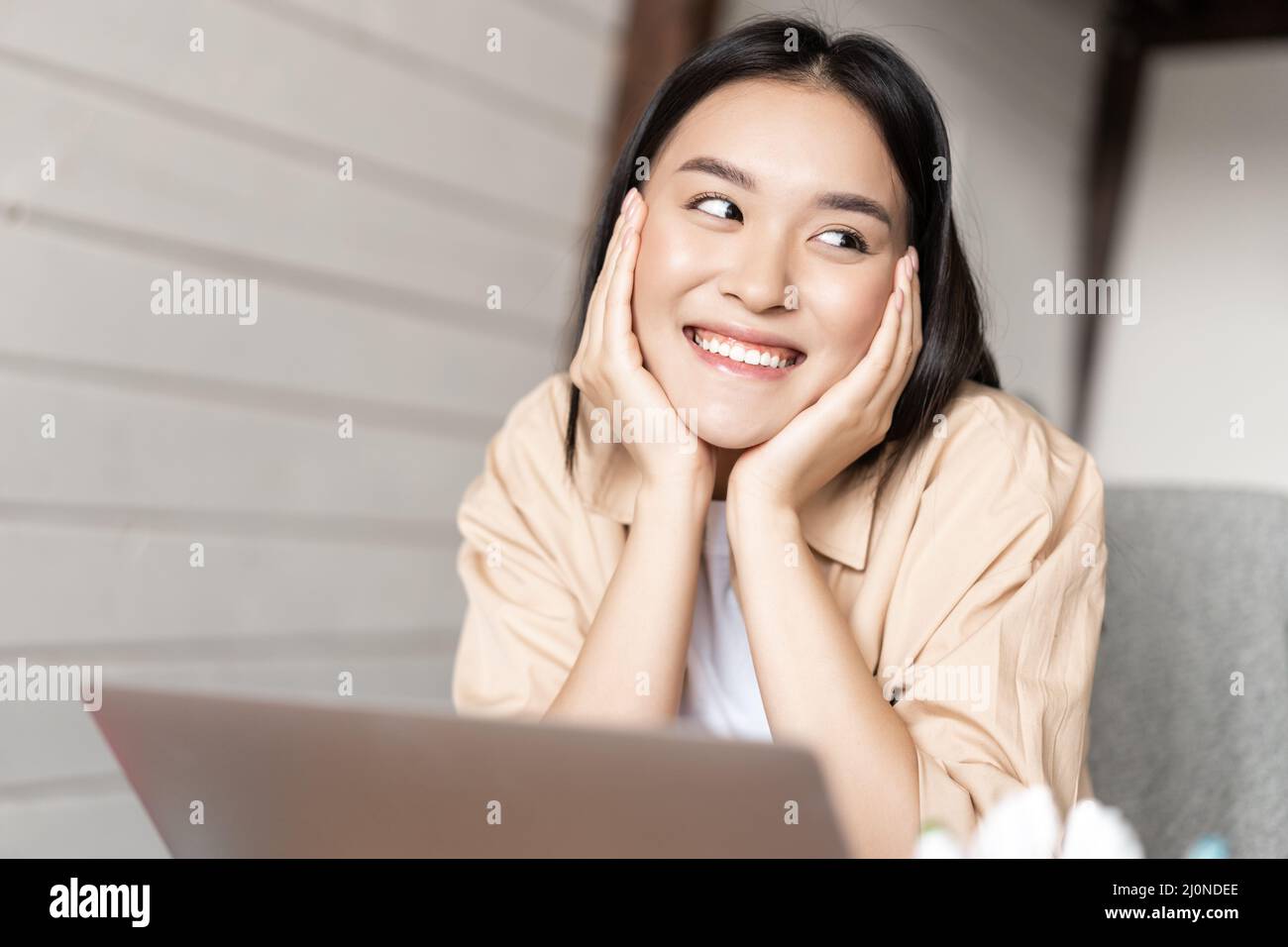 Asian woman smiling while resting, using laptop, watching videos or surfing net on computer, working from home Stock Photo
