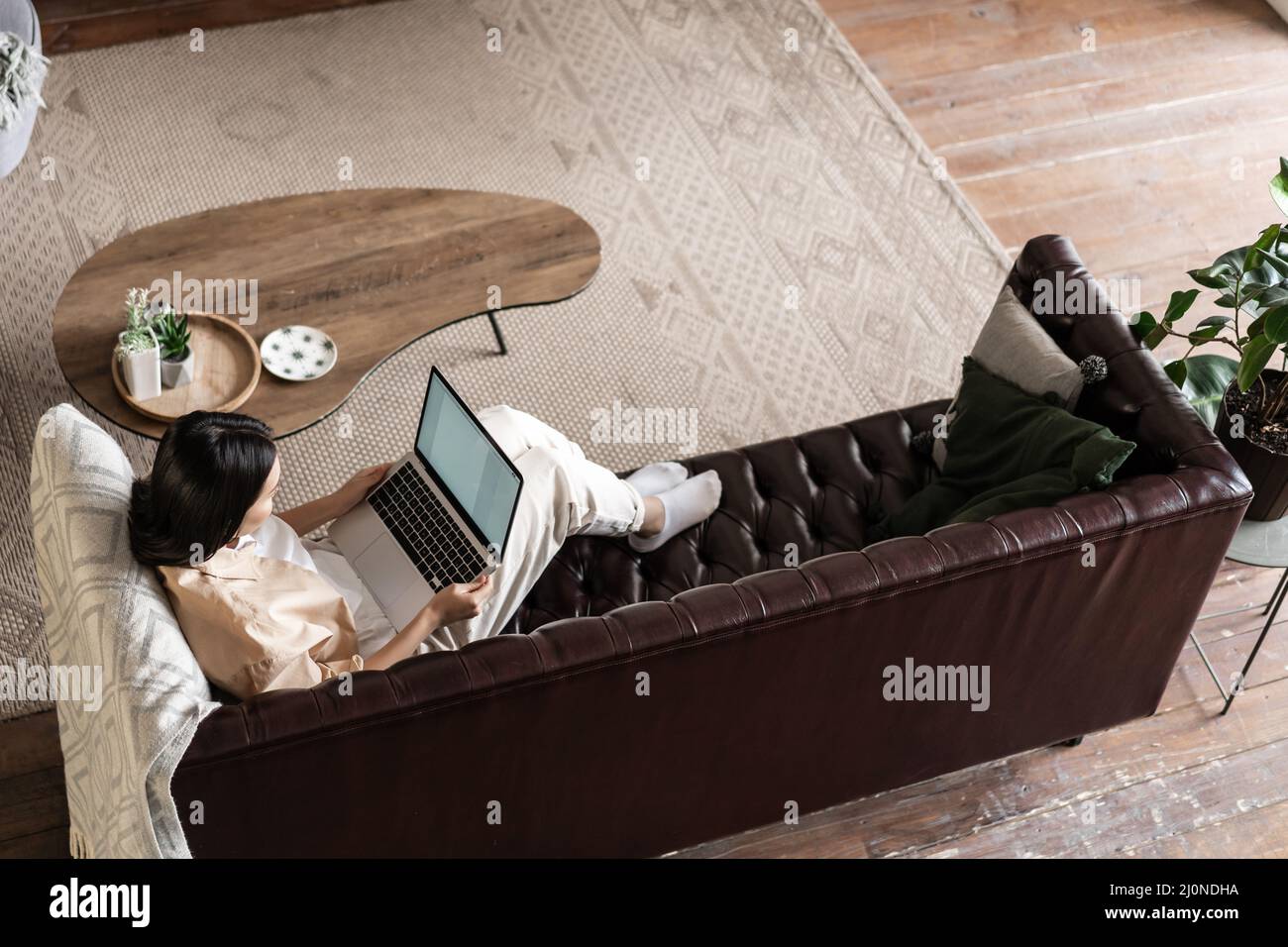 Upper angle shot of asian girl laying on couch, resting with laptop at home, relaxing day on computer Stock Photo