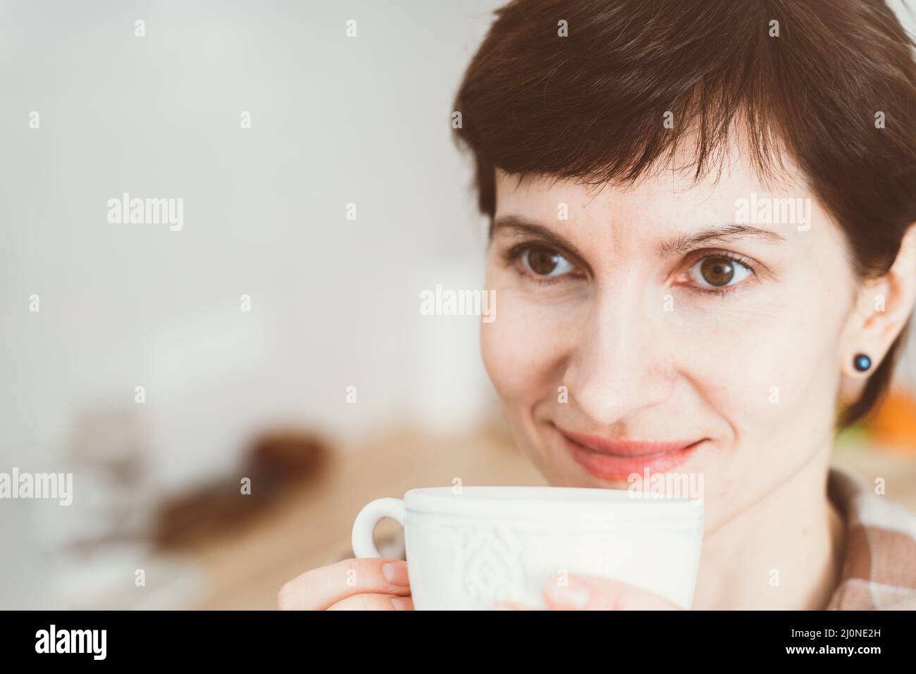 Anosmia, restore sense of smell, lossing due to COVID-19. Close up happy smiling woman sniffing coffee Stock Photo