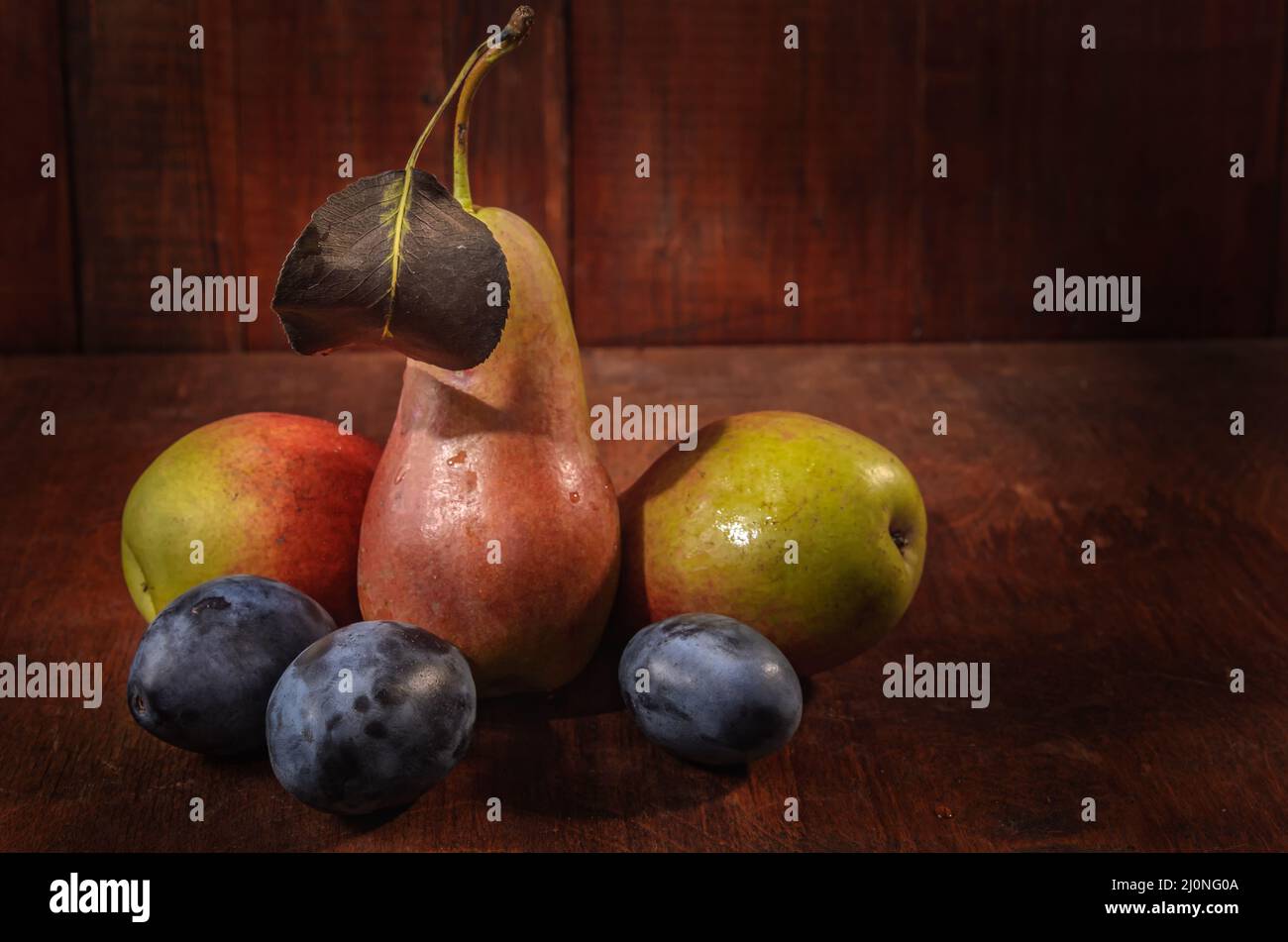 Ripe pears and plums on a dark wooden background in a rustic style Stock Photo
