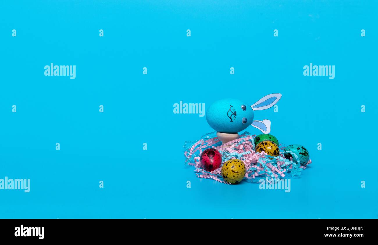 blue Easter egg with ears and colored quail eggs Stock Photo