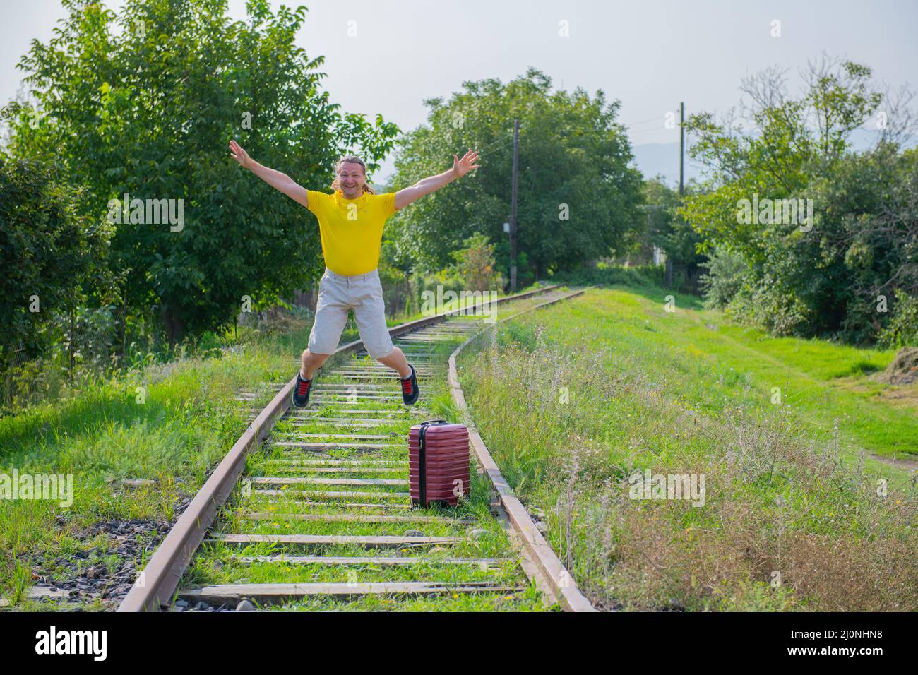 in a yellow jacket, a tourist with a suitcase jumps on the railroad