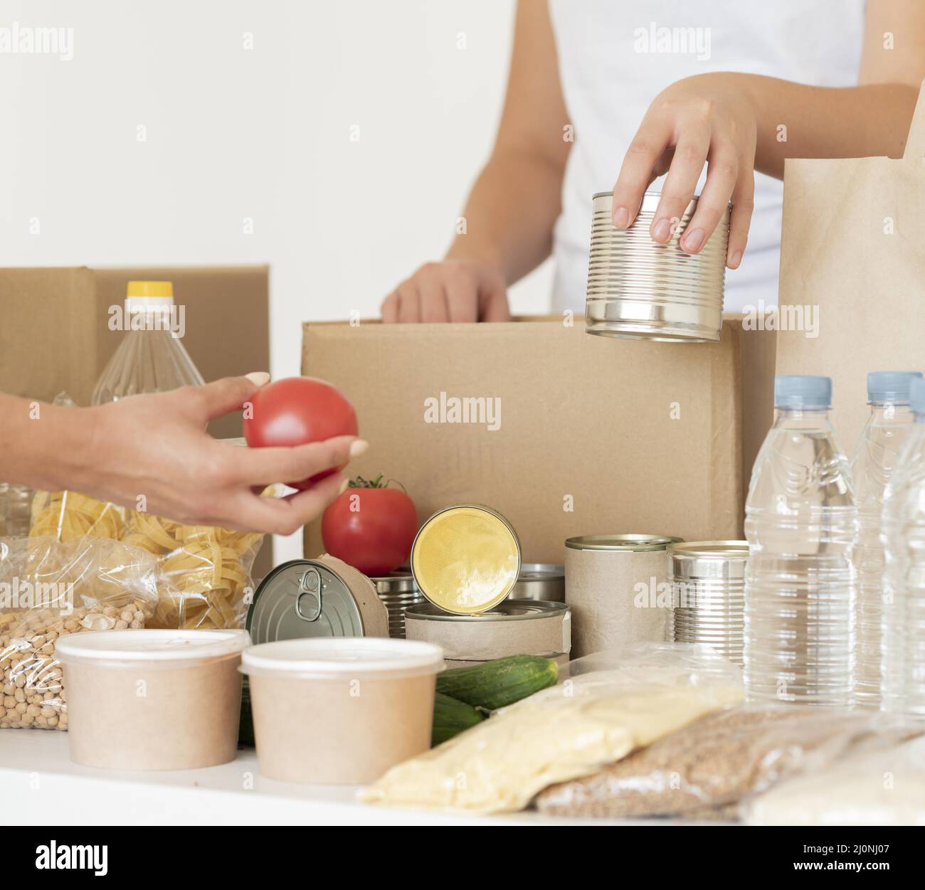 Volunteers putting canned food water donation bag. High quality and resolution beautiful photo concept Stock Photo