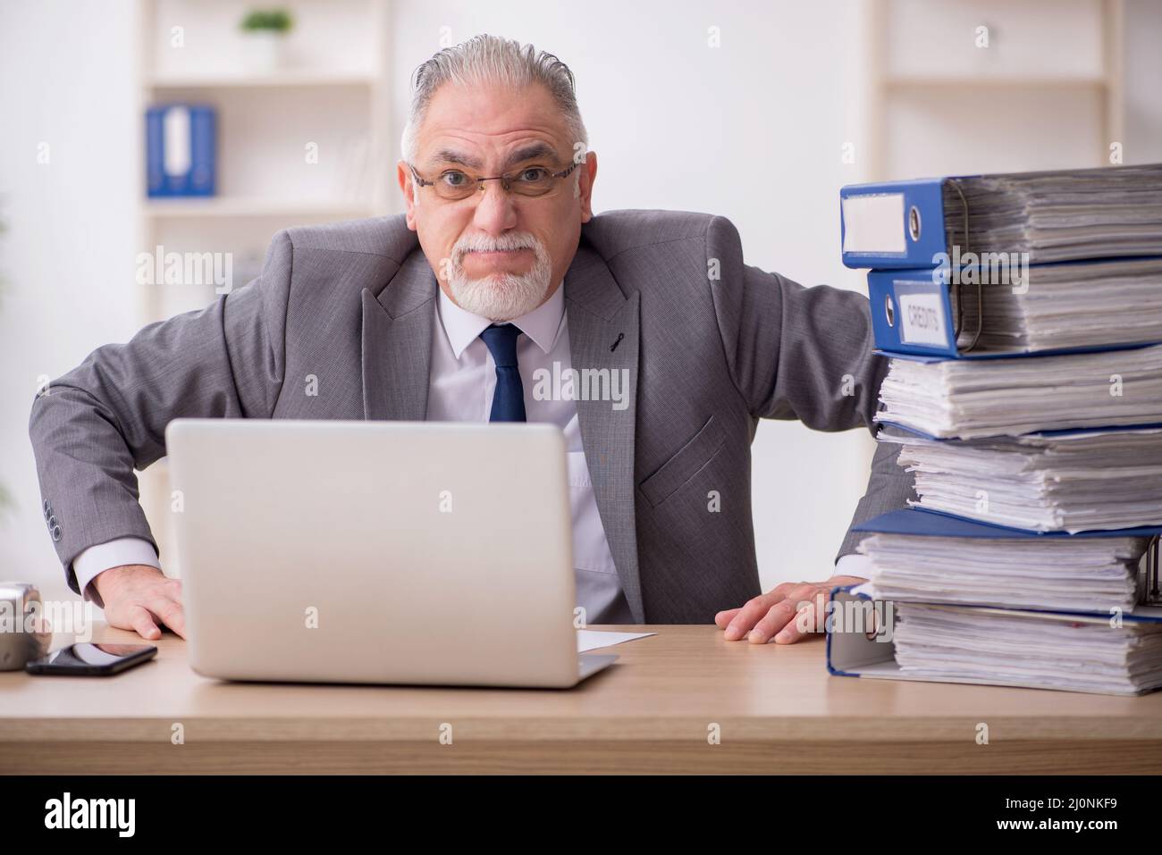 Old male employee unhappy with excessive work in the office Stock Photo