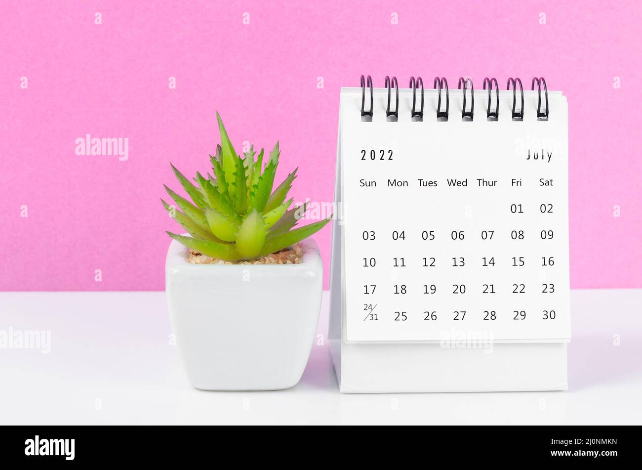 The July 2022 desk calendar with plant pot on pink background. Stock Photo