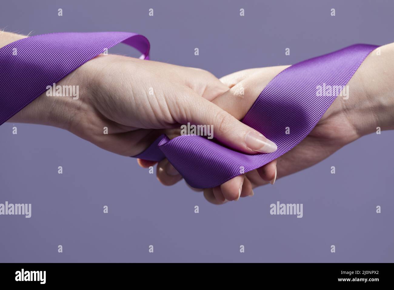 Women hands holding purple satin ribbon. High quality and resolution beautiful photo concept Stock Photo