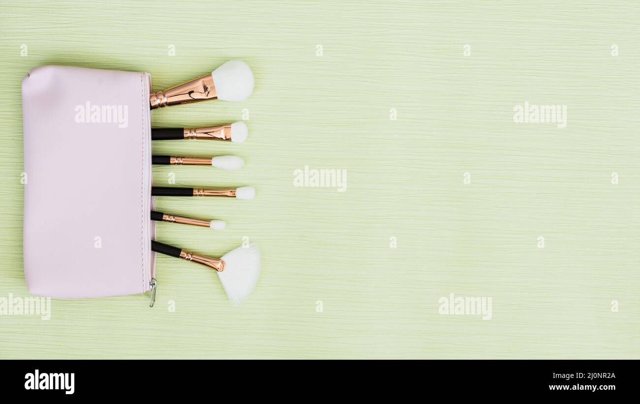 Makeup brushes inside open bag mint green background . High quality and