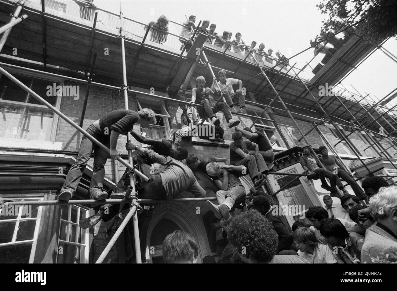 Admires climb scaffolding and occupy every other possible viewpoint to get a glimpse of Muhammad Ali as he pays a surprise visit to a 64-year old widow. Mrs. Chris KotuiskI  in Leonard Road,Lozells. She has been a fan of his since he began boxing in 1961 but is now crippled with arthritis.9th August 1983 Stock Photo