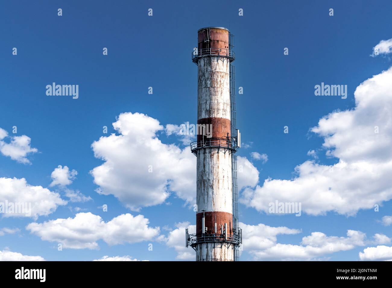 Large red white factory chimney against a cloudy summer sky Stock Photo