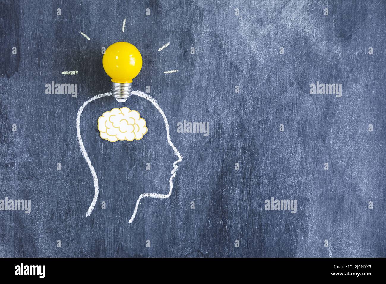 Yellow light bulb paper cutout brain outline face made with chalk blackboard. High quality and resolution beautiful photo concep Stock Photo