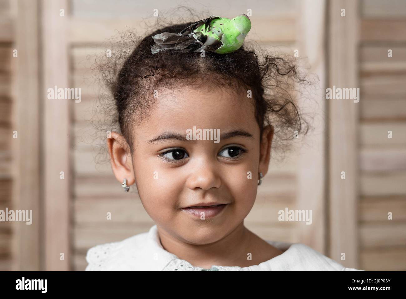 Adorable mixed-race little girl with parrot hair accessory Stock Photo