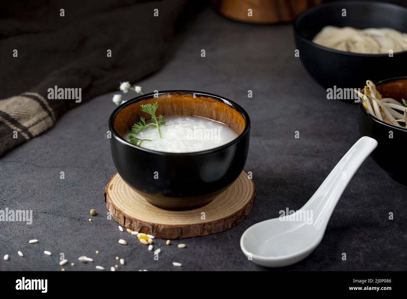 Rice soup black bowl wooden support white spoon . High quality and resolution beautiful photo concept Stock Photo