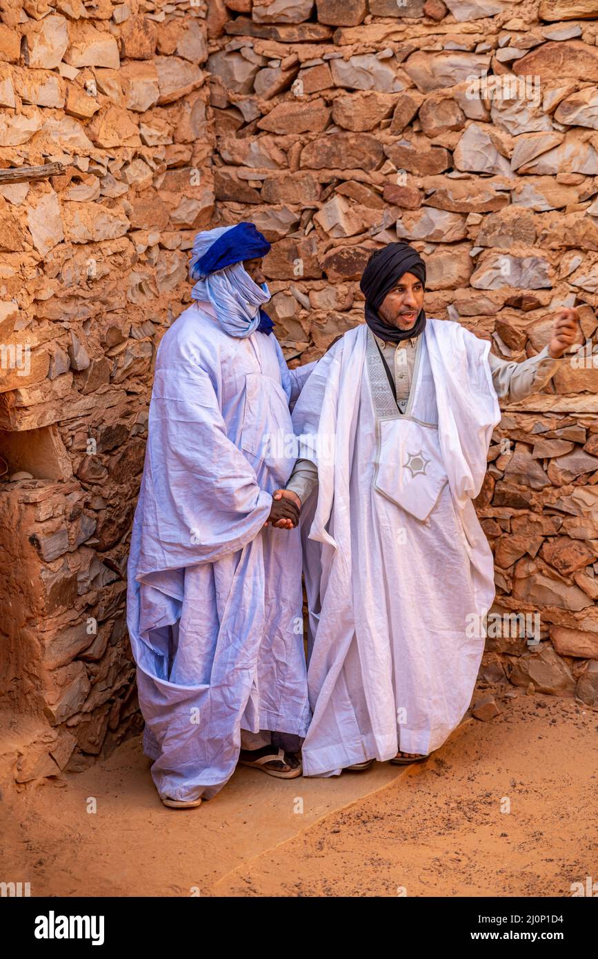 Two Mauritanian adult men in traditional blue boubou and turbans shaking hands, Chinguetti, Adrar Region, Mauritania Stock Photo