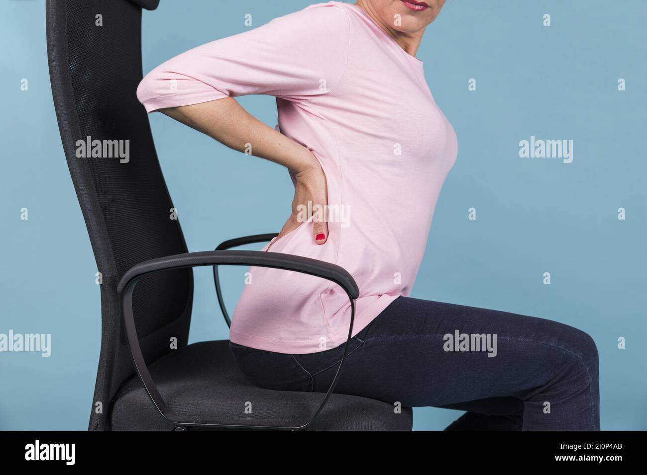 Woman sitting chair having backache blue backdrop. High quality and