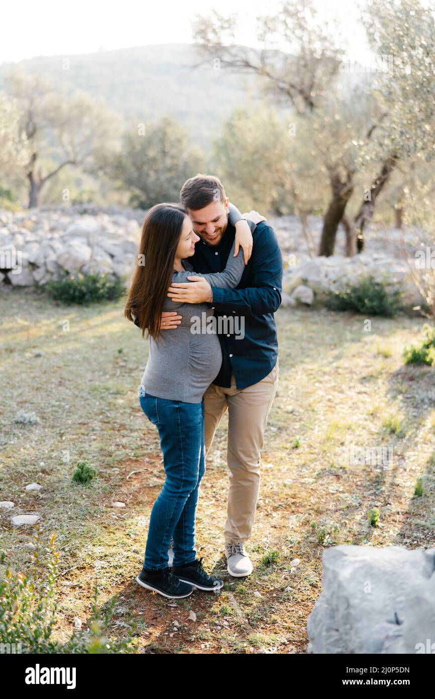 Man hugging pregnant woman in park Stock Photo