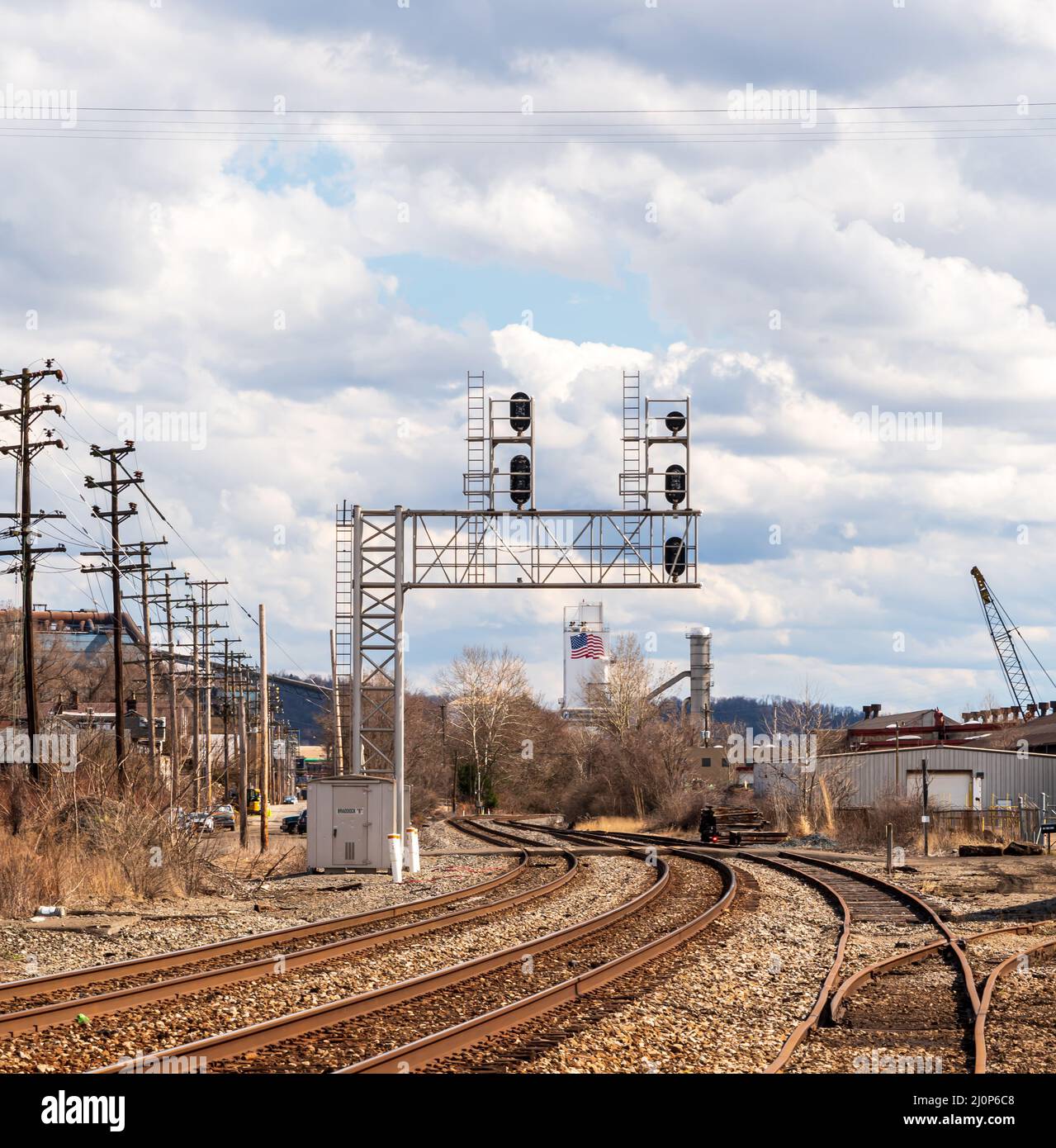Overhead railroad signals above train tracks in an industrial area in