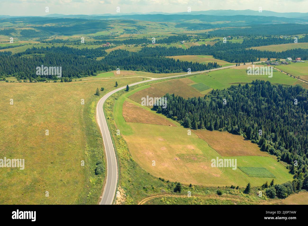 Panoramic aerial view of the countryside, country road, and cultivated and uncultivated fields in the hills Stock Photo