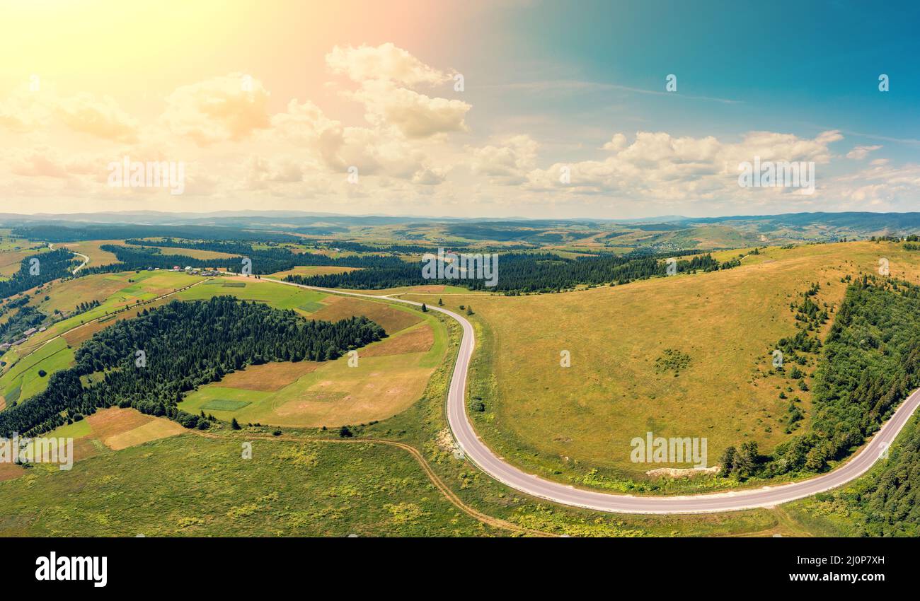 Panoramic aerial view of the countryside, country road, and cultivated and uncultivated fields in the hills Stock Photo